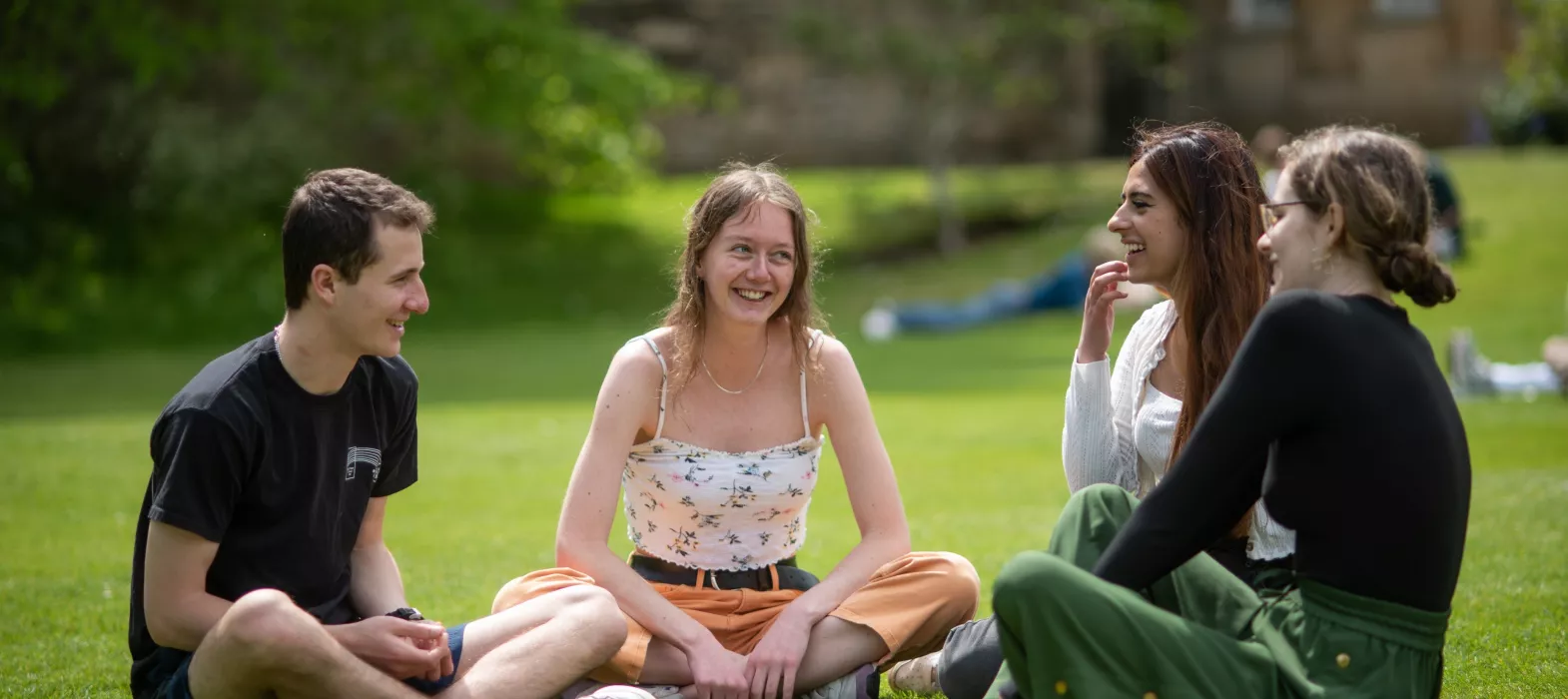 Four students laughing in the gardens
