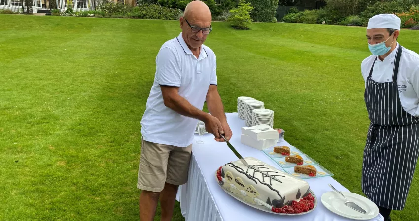 Steve cutting into his cake in the New College gardens