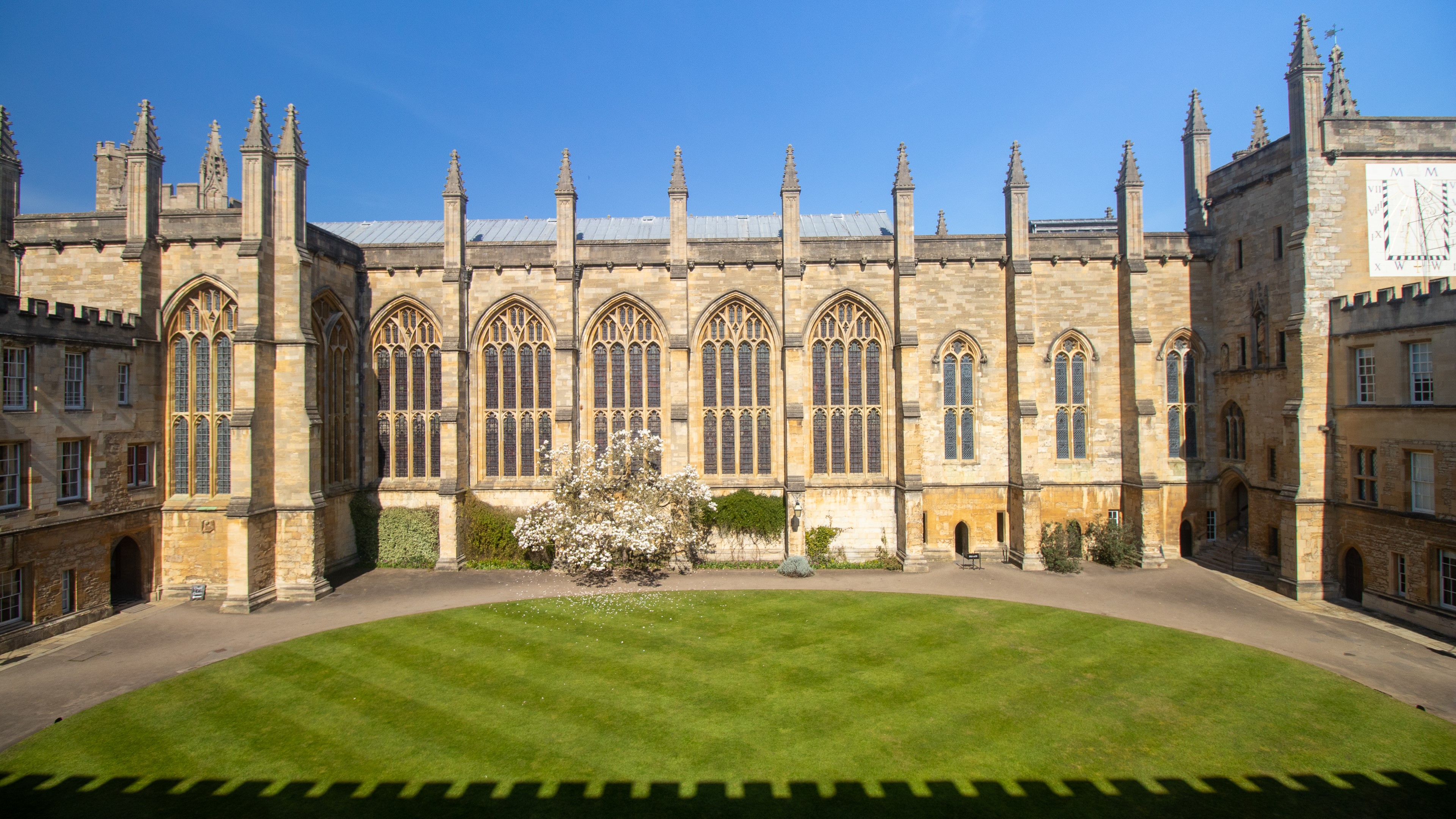 Gothic building with lawn in front and shadow of crenellations