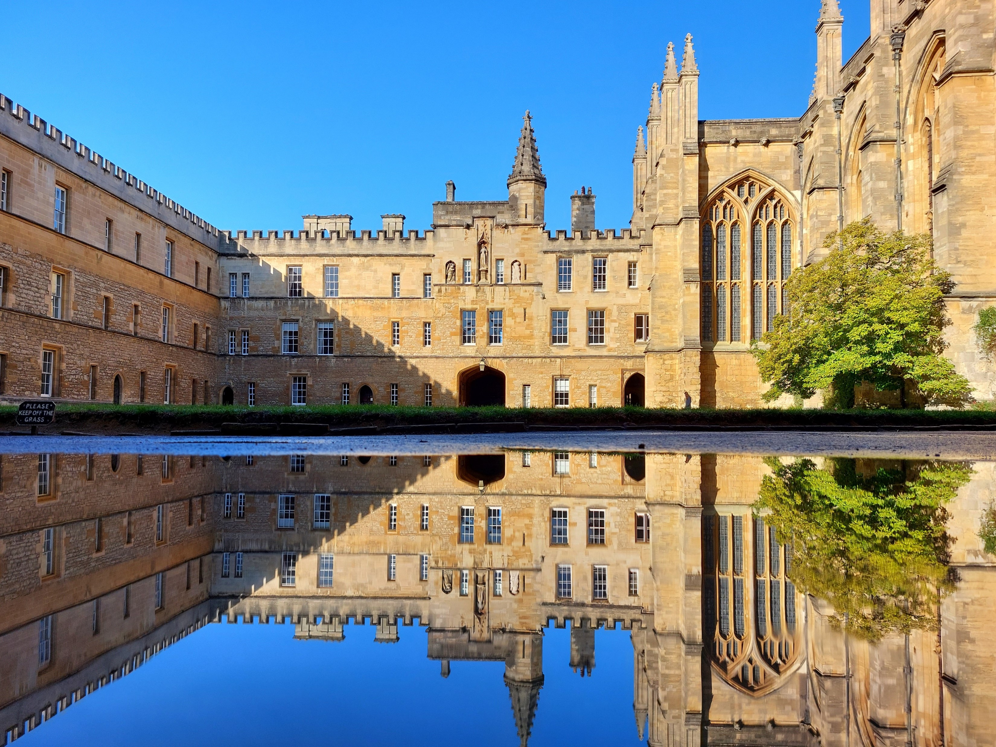 Gothic building and blue sky reflected in puddle