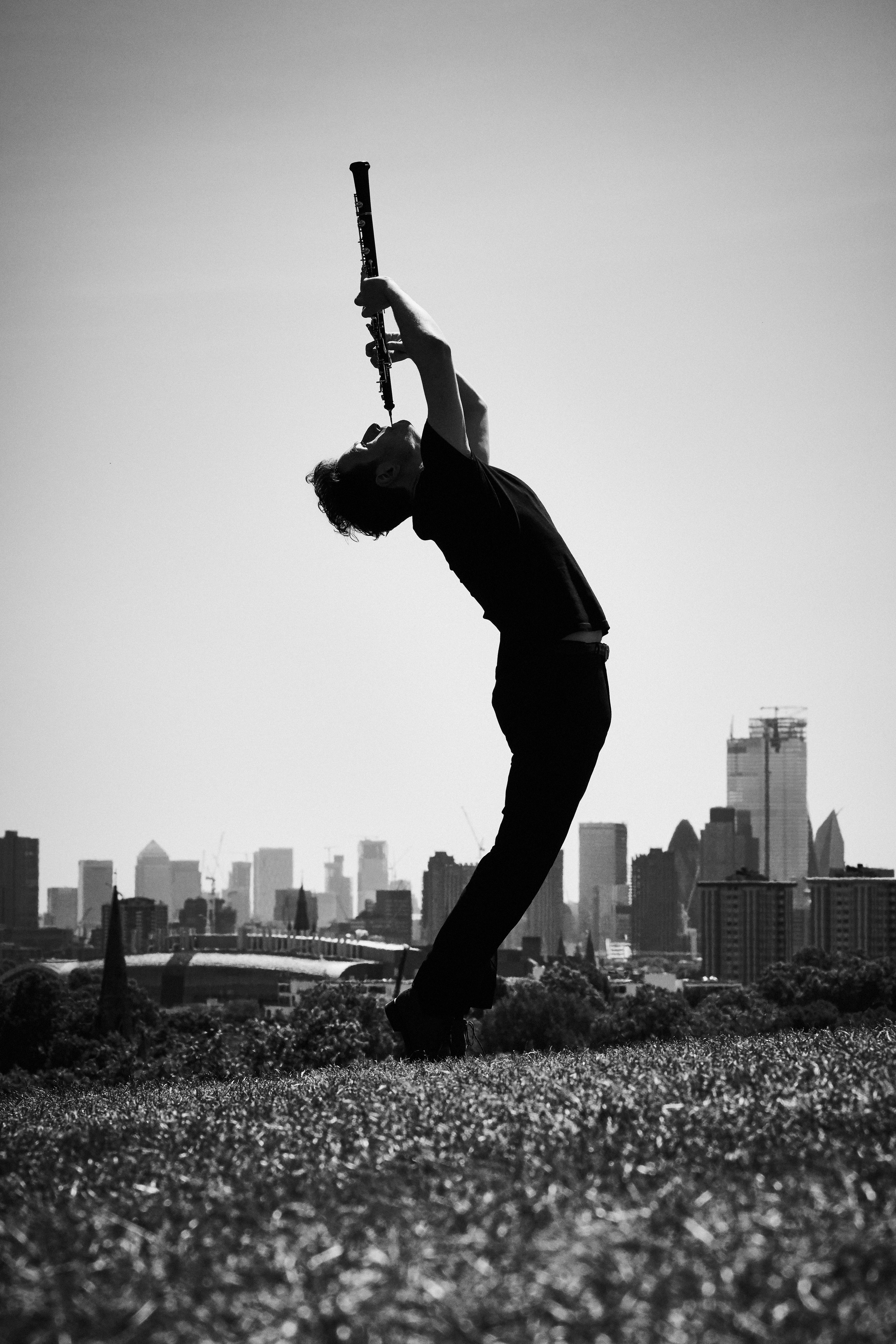 Black and white photo of oboist playing his instrument in a park overlooking London