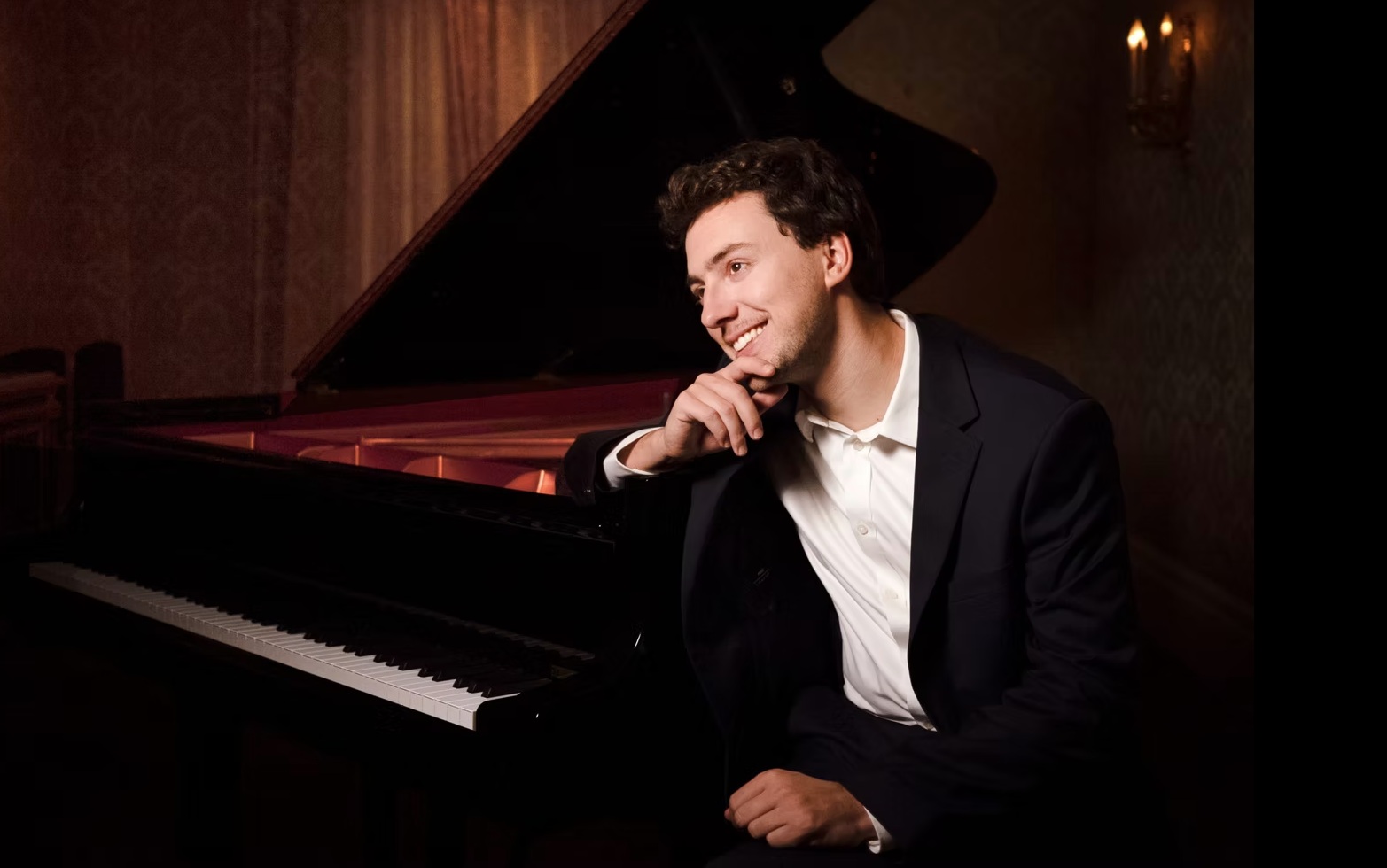 Man sitting next to piano smiling