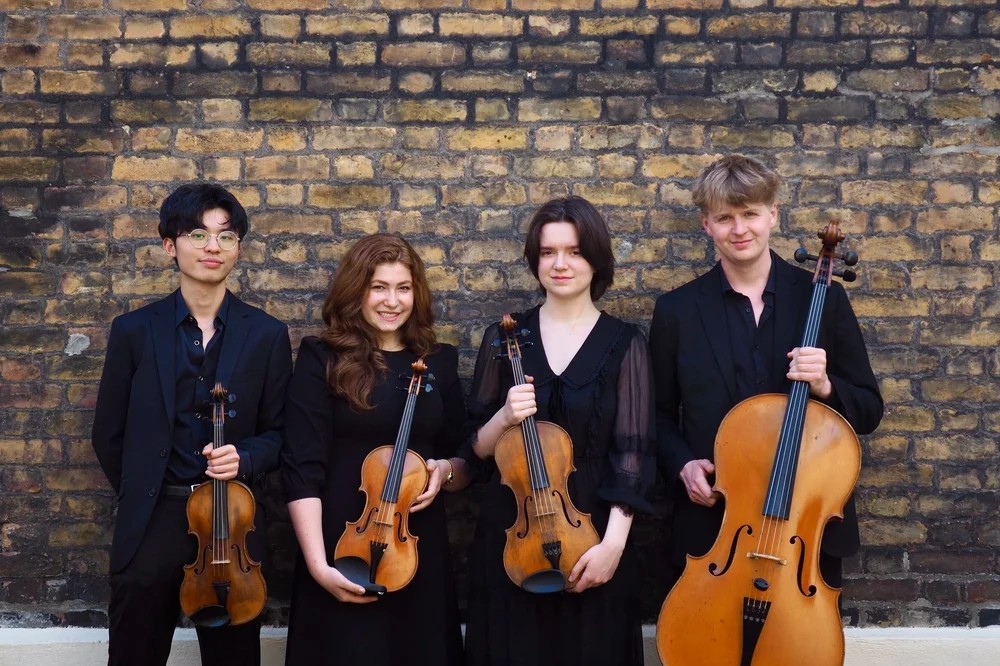 Image showing the four musicians of the Neruda Quartet holding their instruments in front of a brick wall