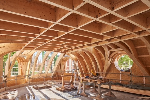 View from inside the roof, with timber beams in geometric formation and a circular hole