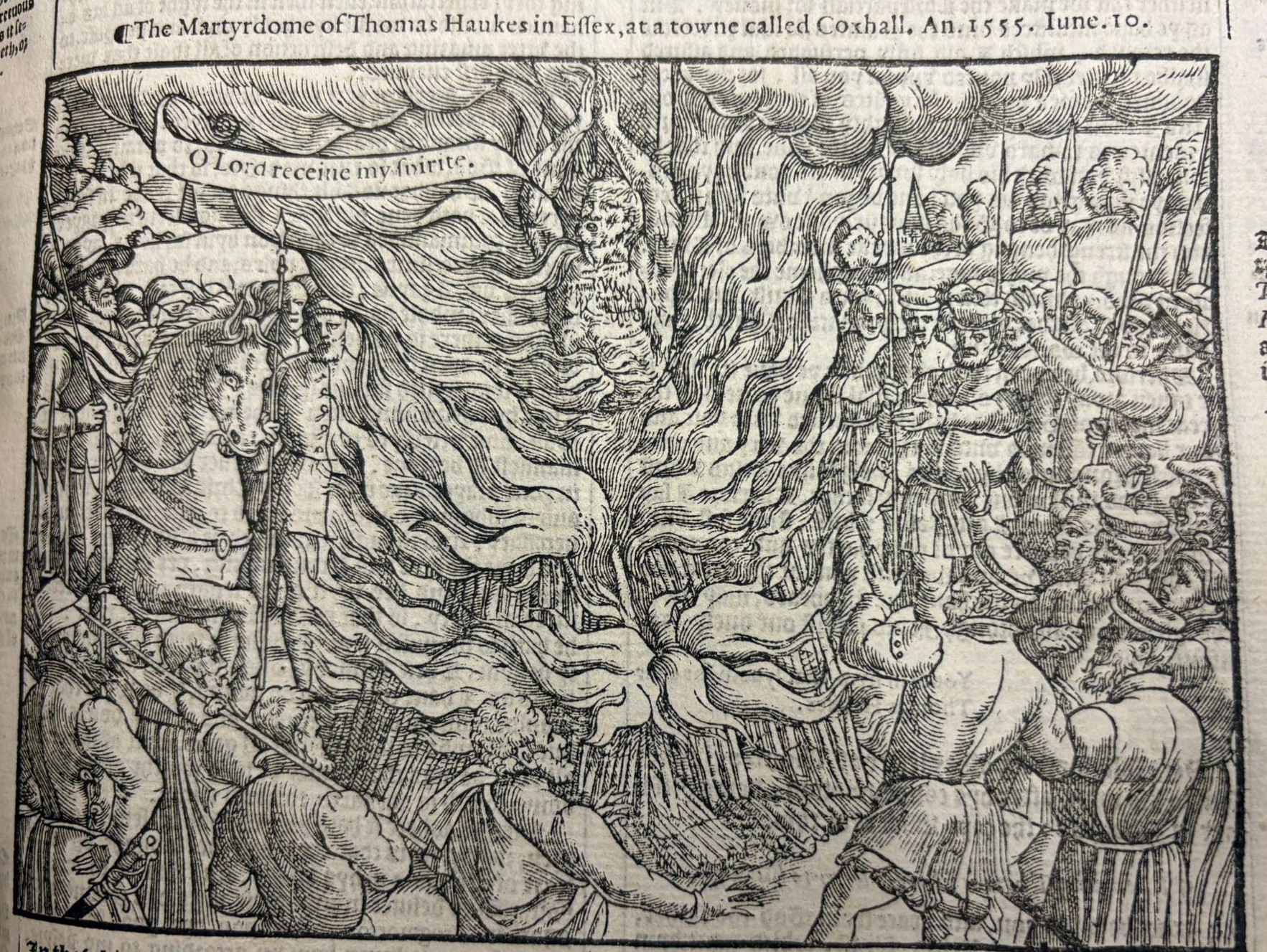 A woodcut print of a man being burnt at the stake.