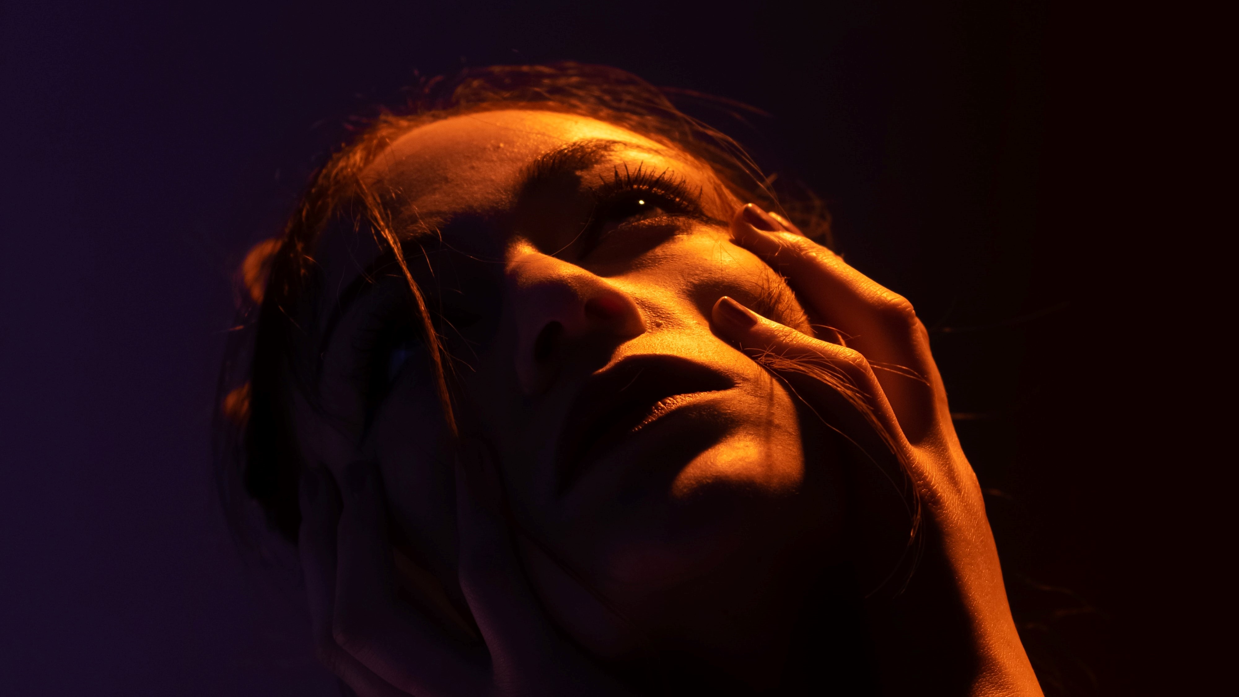 Woman clutching at her half-lit face