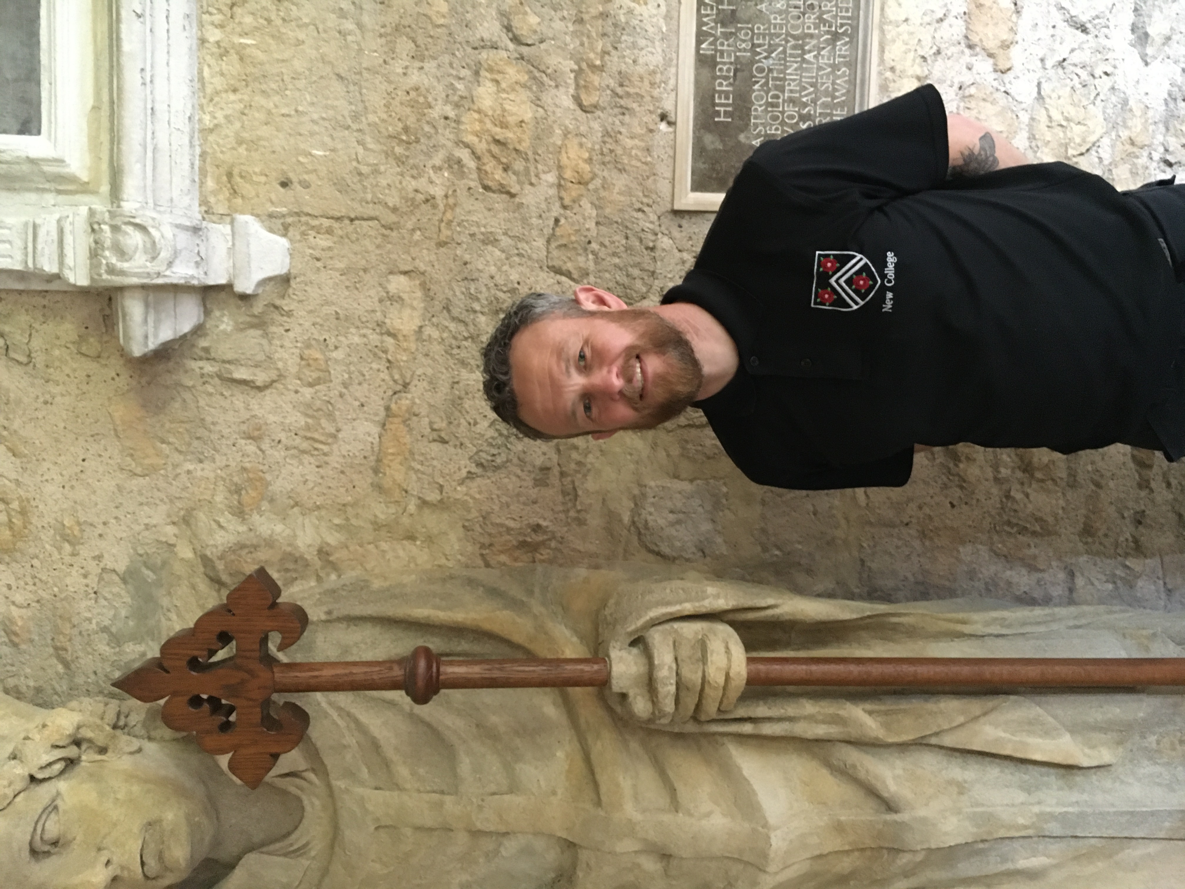 Brendan standing next to a statue with a wooden staff (that he created)