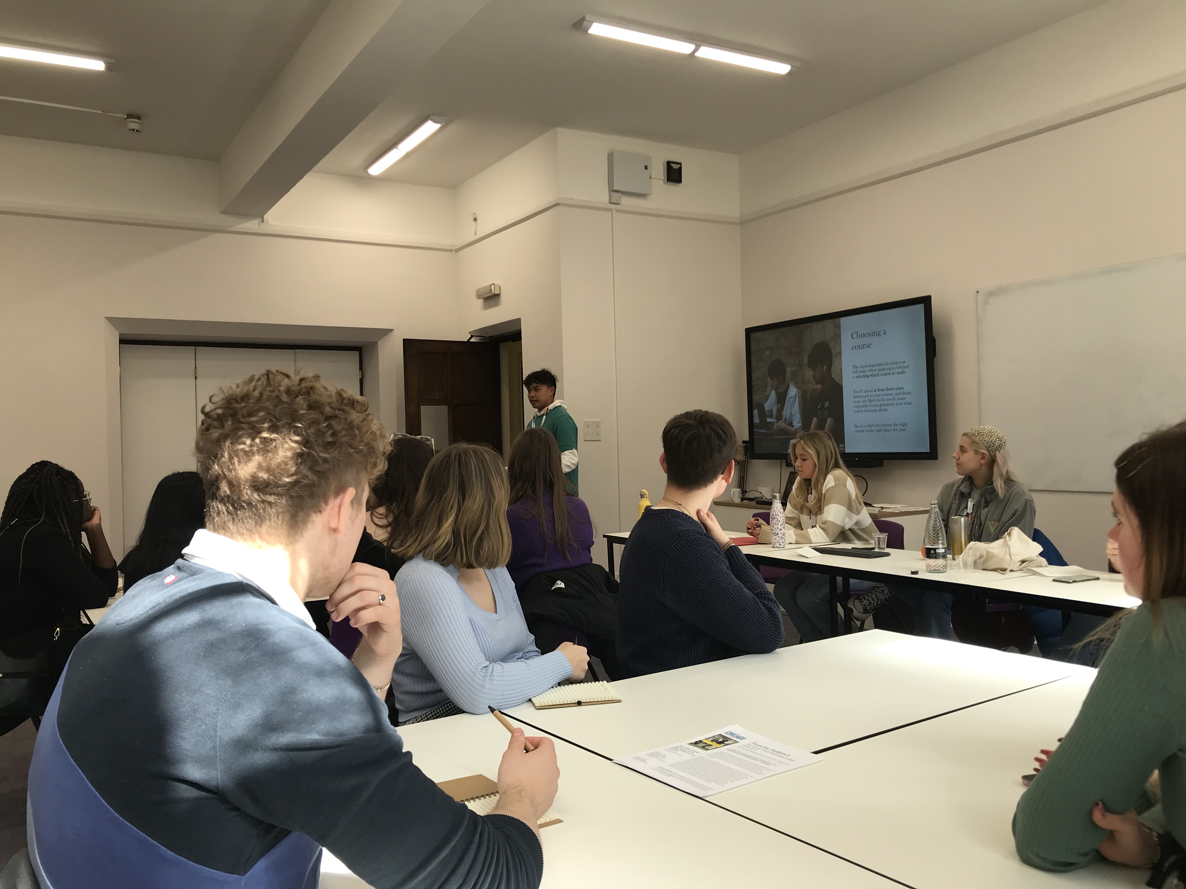 Gabriel delivering a session to prospective students sat around white tables