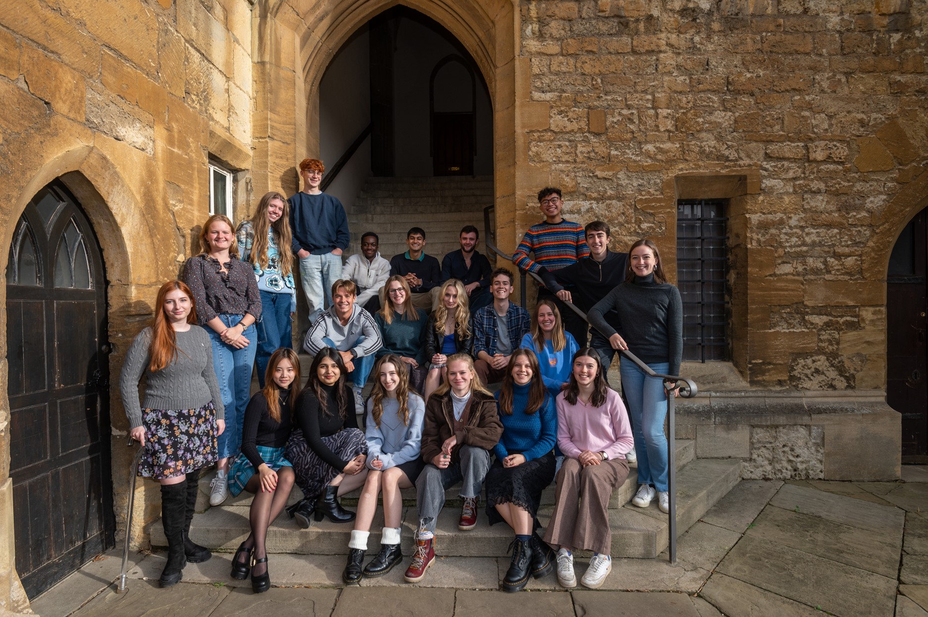 A group of students sat and stood on steps, smiling at the camera