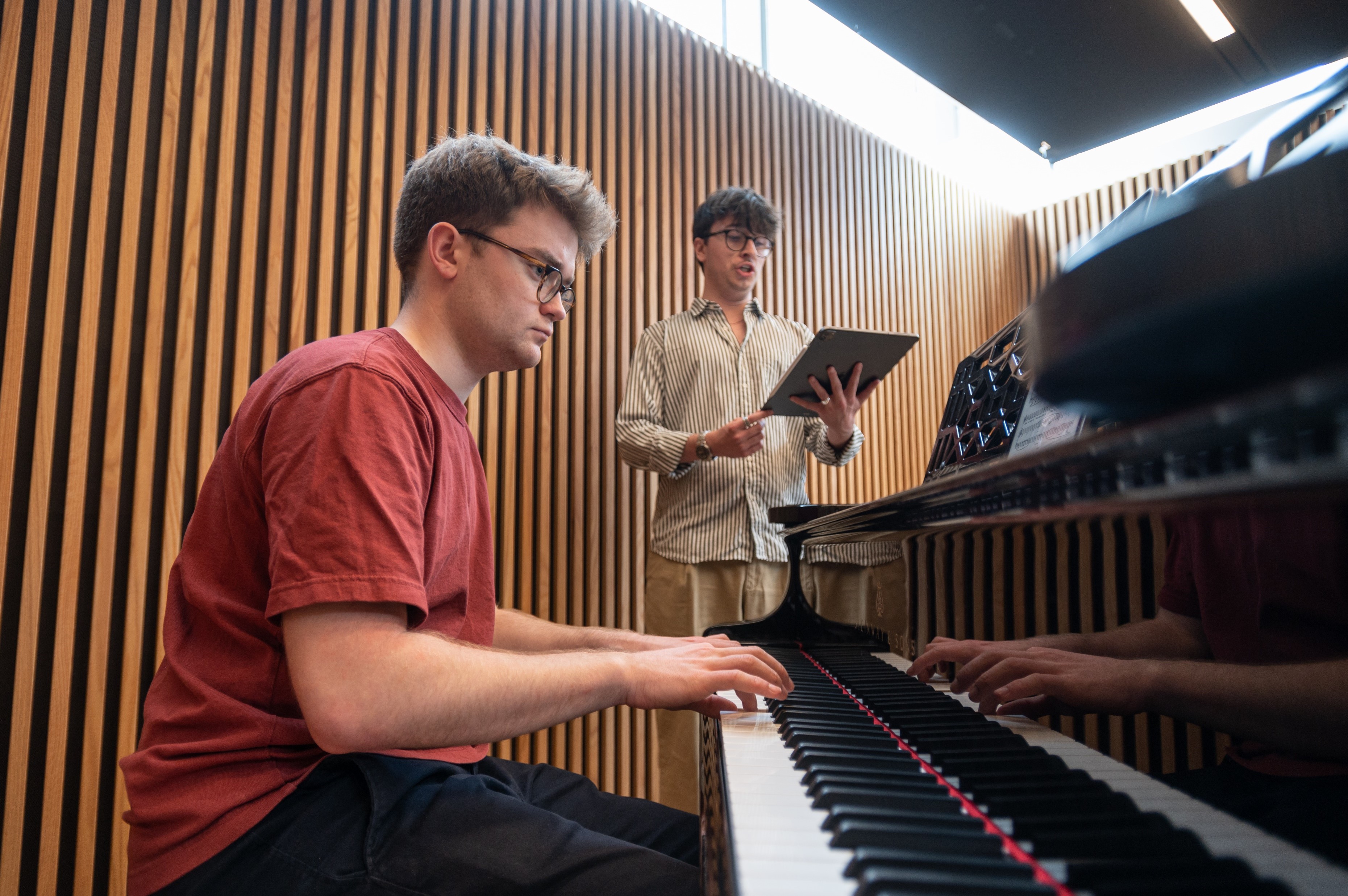 Student singing while another accompanies on a piano