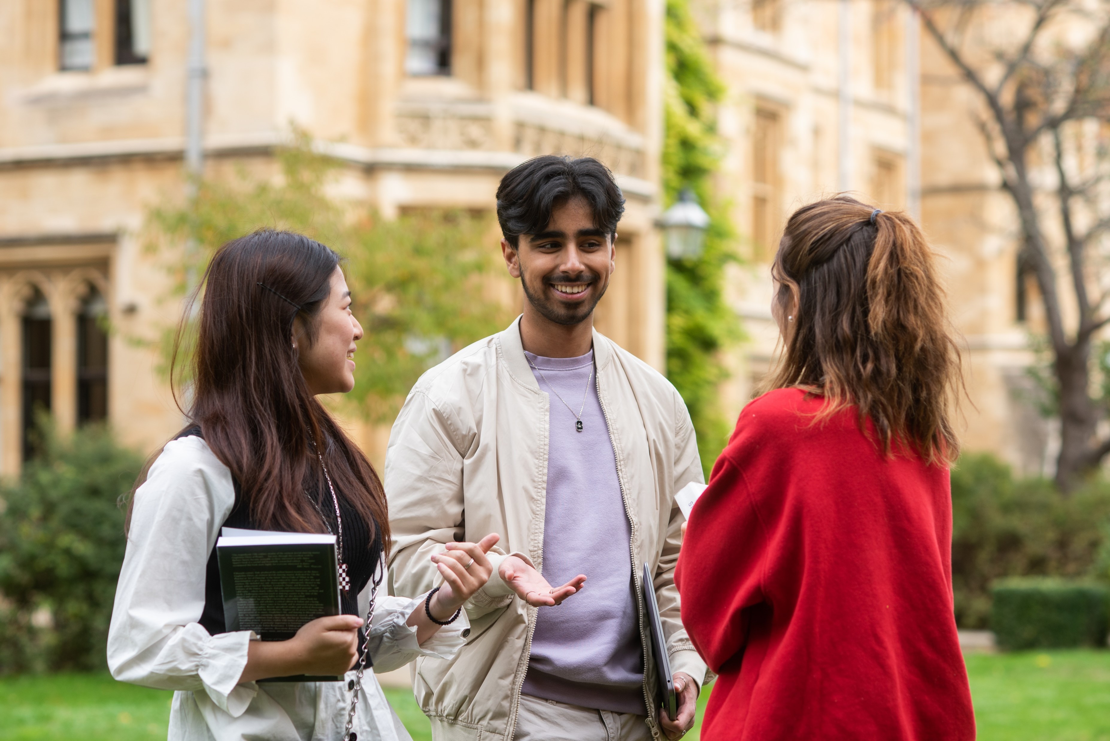 Three students smiling with buildings behind