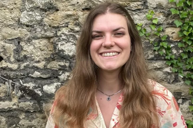 Sarah Pelle smiling in front of a brick wall