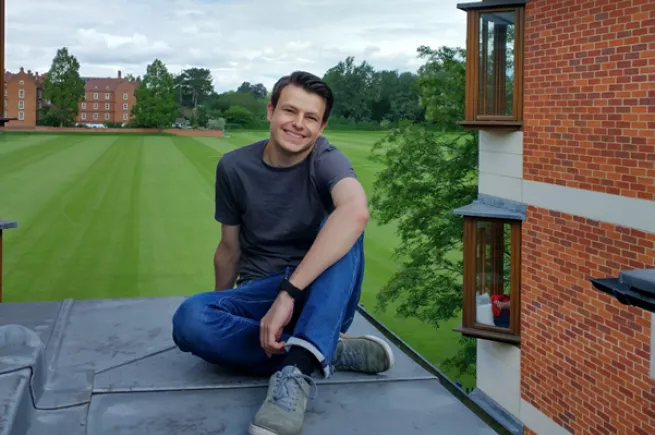 Aidan sits on the roof of the MCR Pavilion with the sports fields in the background