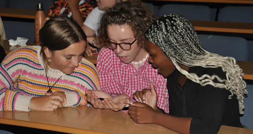 Three students holding cockroaches