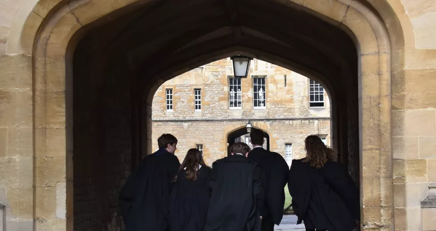 Gowned students walking through an arch