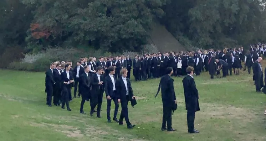 Students lining up for photographs in the Gardens, with the Mound in the background