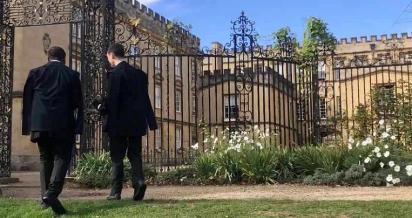 Two students in sub fusc by the iron screen in Garden Quad