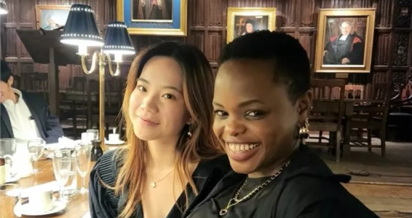 Two students smiling at the camera in a medieval dining hall