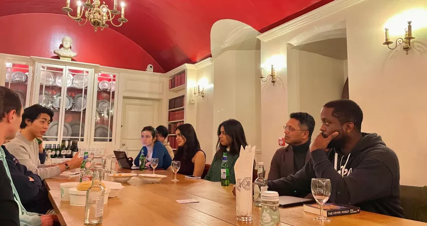 Group of people sitting around a table talking, with drinks