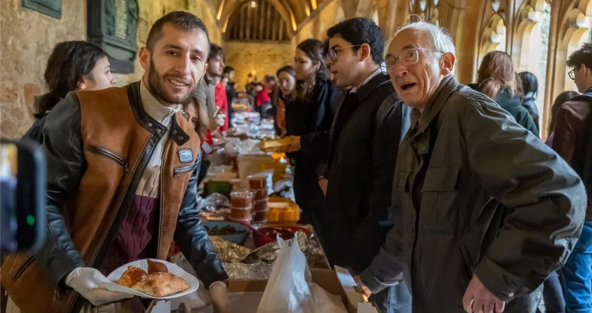 People pose for a photo while one is served food by the other