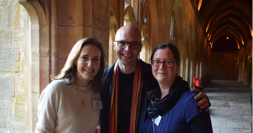 Three people smile at camera in Cloisters