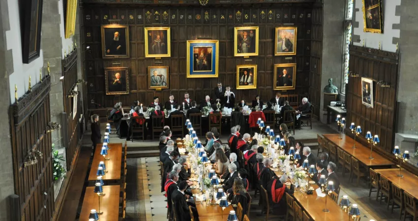 People in formal gowns sat in a medieval dining hall