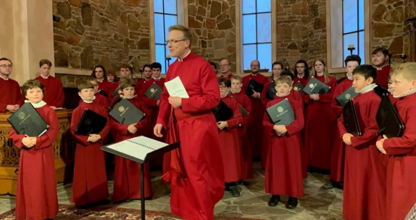 Choir and conductor standing in red robes