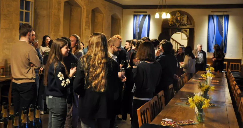 People gathered in a Long Room with drinks and long tables either side