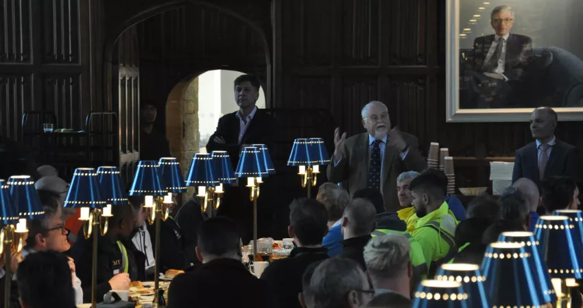 Bursar giving a speech to people sat at long tables