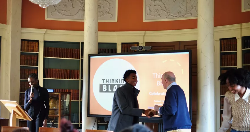 A student is congratulated by the Warden