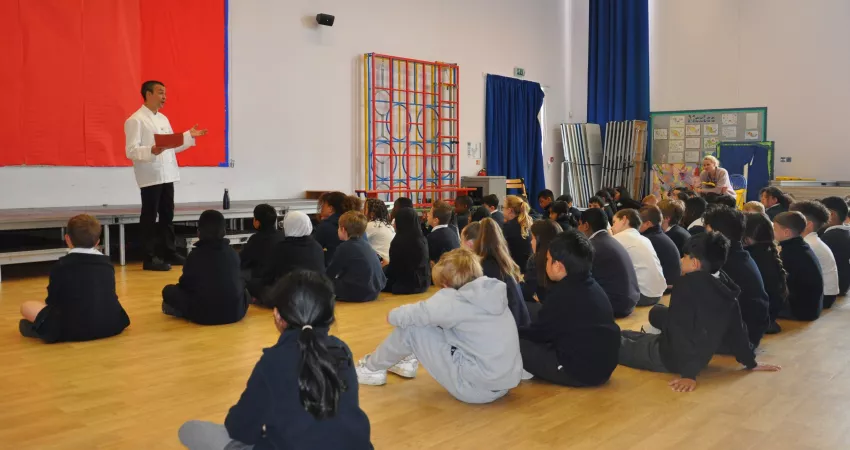 Sam presents to a large group of seated students in a school hall