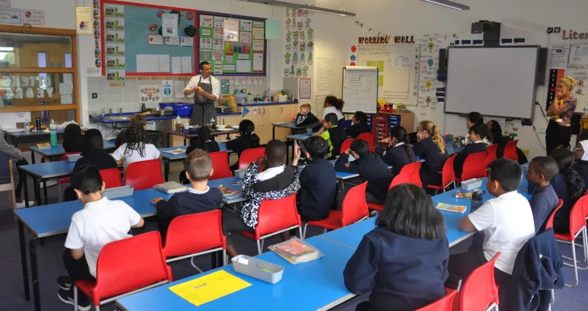 A chef demonstrates to students in a classroom