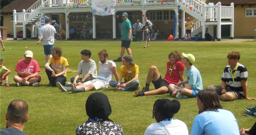 People sitting on the grass of a large sports field