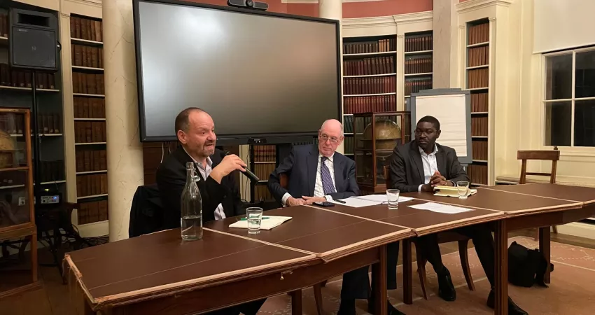 Philippe Sands speaks into a mic whilst Miles Young and Dapo Akande listen