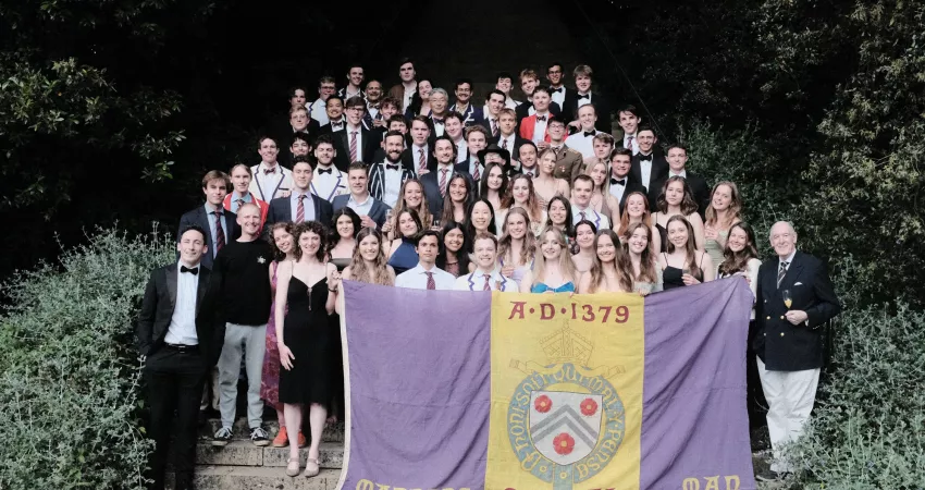 The New College Boat Club post for a picture in front of the New College mound holding a boat club flag.