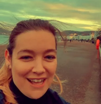 Shelby smiling at the camera with a beach and hills in the background