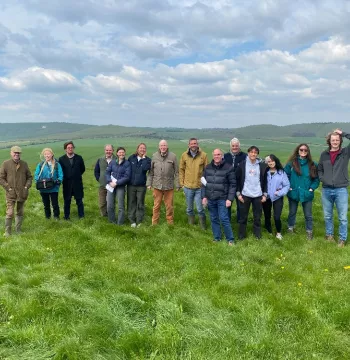 A group of people in a field with hills in the background
