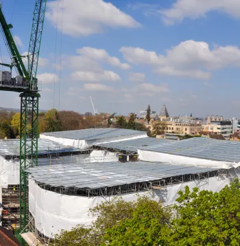 A curved, 3-sided quad being built, covered by sheets