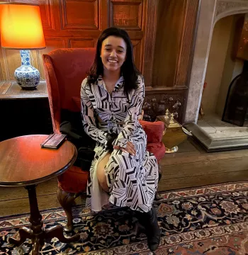 A woman sitting in a large chair with wood panelling behind
