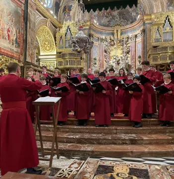 A choir wearing red robes, performing in an elaborately decorated church