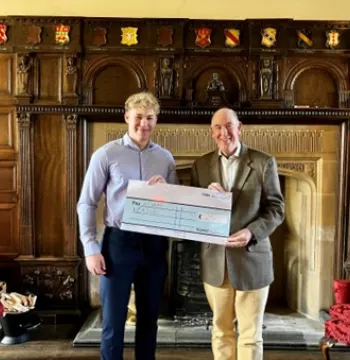 Adam stands with the Warden holding a cheque