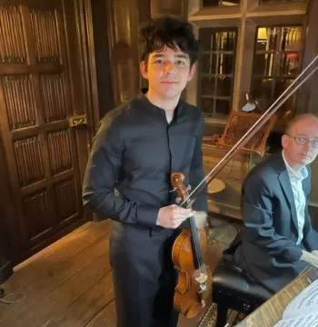 George Lawson holds a violin and stands besides Andew Lawson on the piano