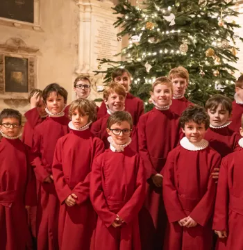 New College choir stands in front of a Christmas tree in the Chapel