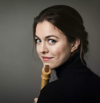 Woman holding a recorder, turning around to look at the camera